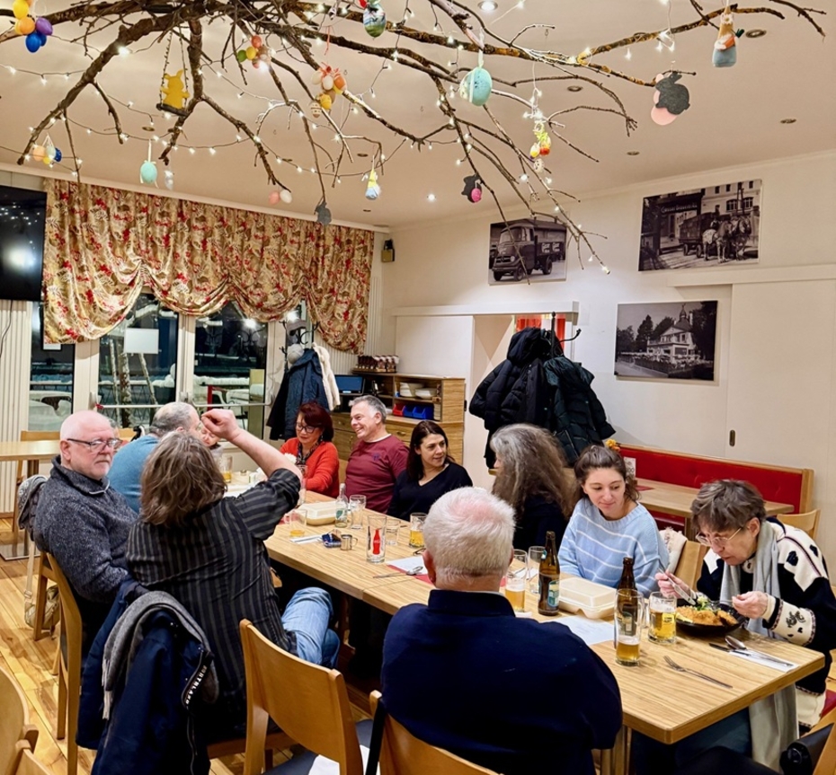 Eine Gruppe von Menschen sitzt in einem Lokal an einem großen Tisch