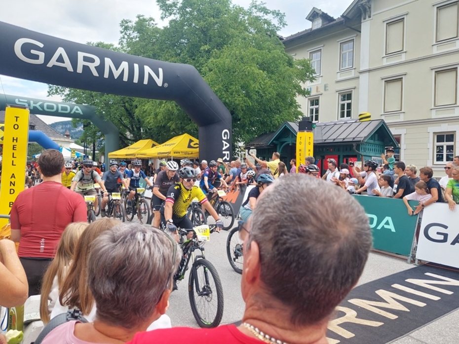 Mehrere Radfahrer mit Startnummern fahren durch den Startbogen beim Mountainbikerennen