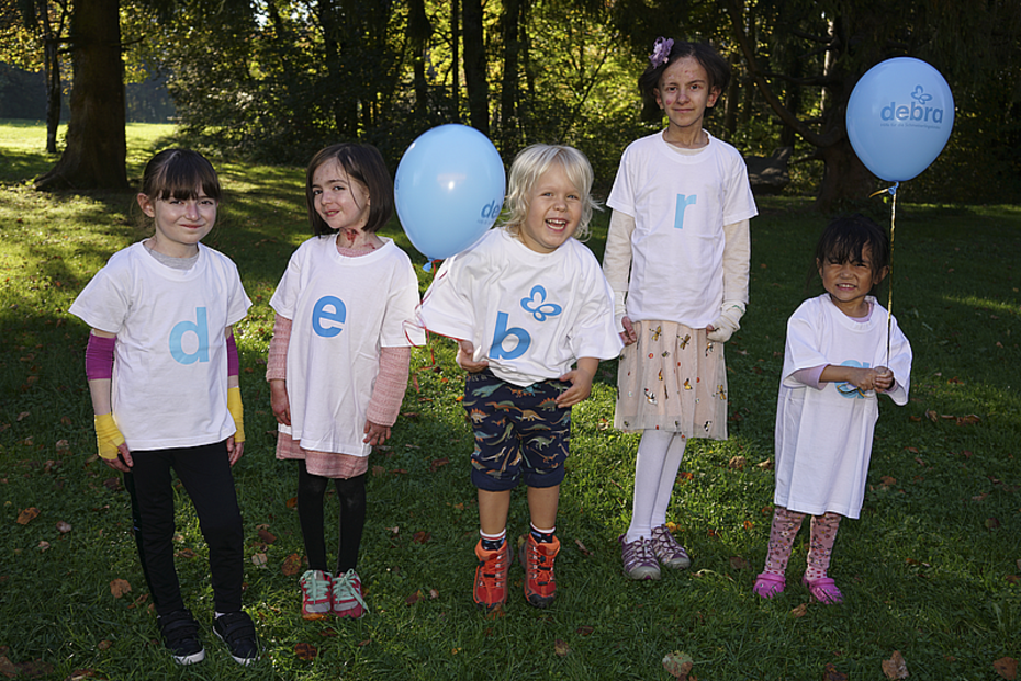 Schmetterlingskinder mit Luftballons auf einer Wiese