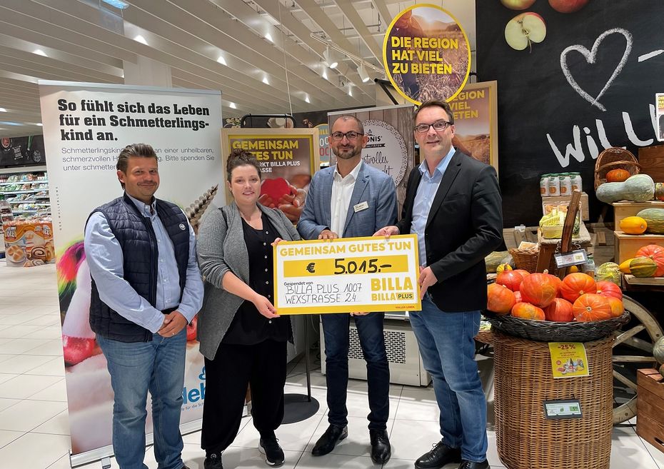 Vier Personen mit einem Spendenscheck stehen im Supermarkt