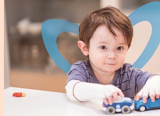 Schmetterlingskind mit stilisierten blauen Flügeln spielt mit Holzautos
