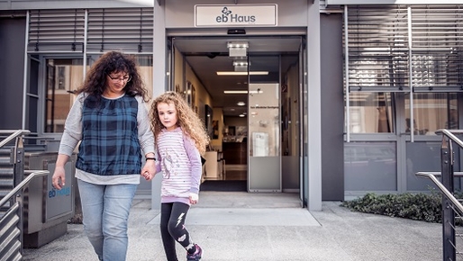 Eingang des EB-Haus Austria, im Vordergrund Schmetterlingskind mit Mutter