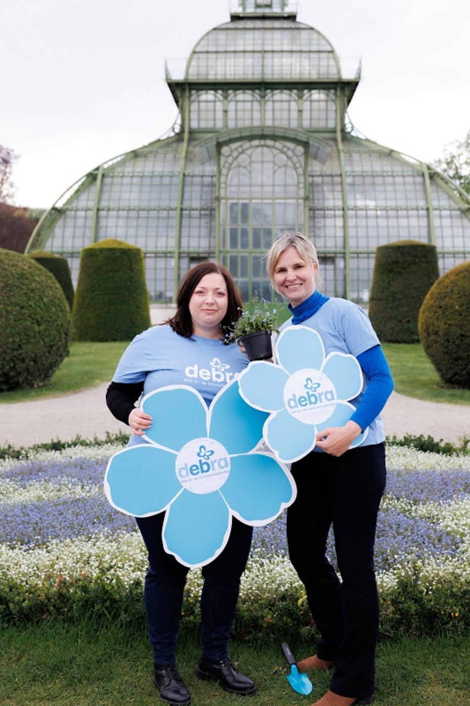 Zwei Frauen stehen in einem Park und halten große Schilder in Blumenform