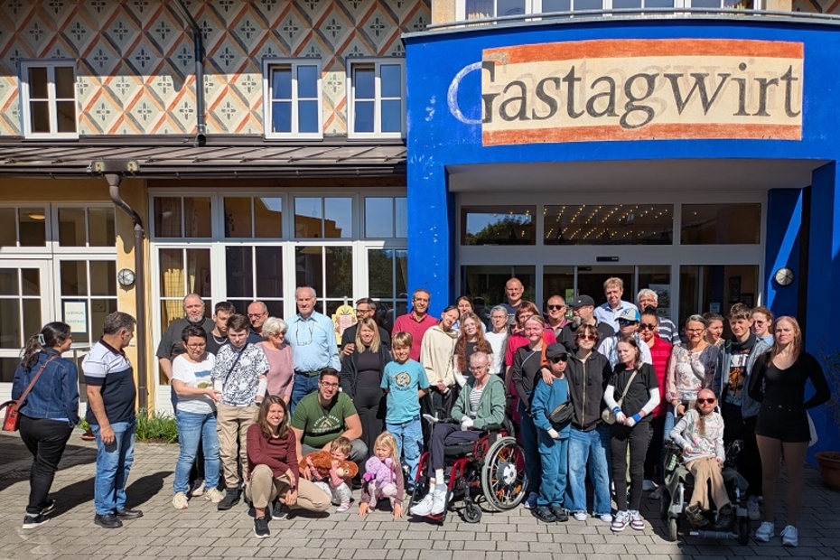 Eine große Gruppe von Menschen vor dem Eingang eines Gasthauses