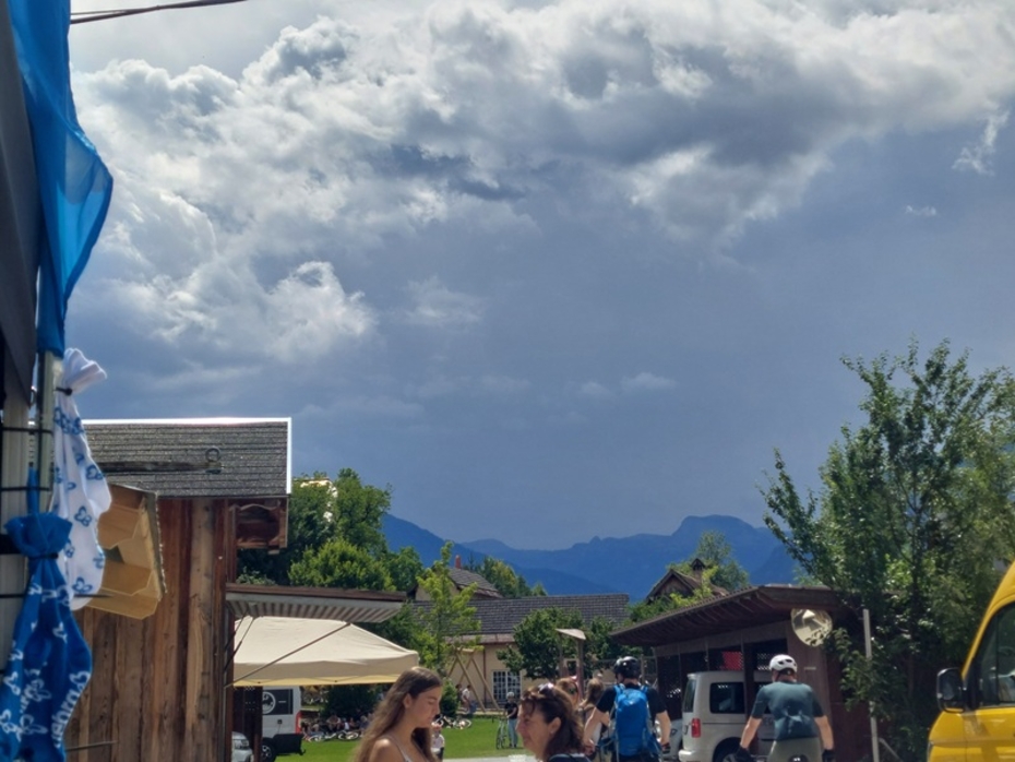 Blick auf düstere Gewitterwolken, links im Vordergrung die DEBRA Austria Beachflage DEBRA 