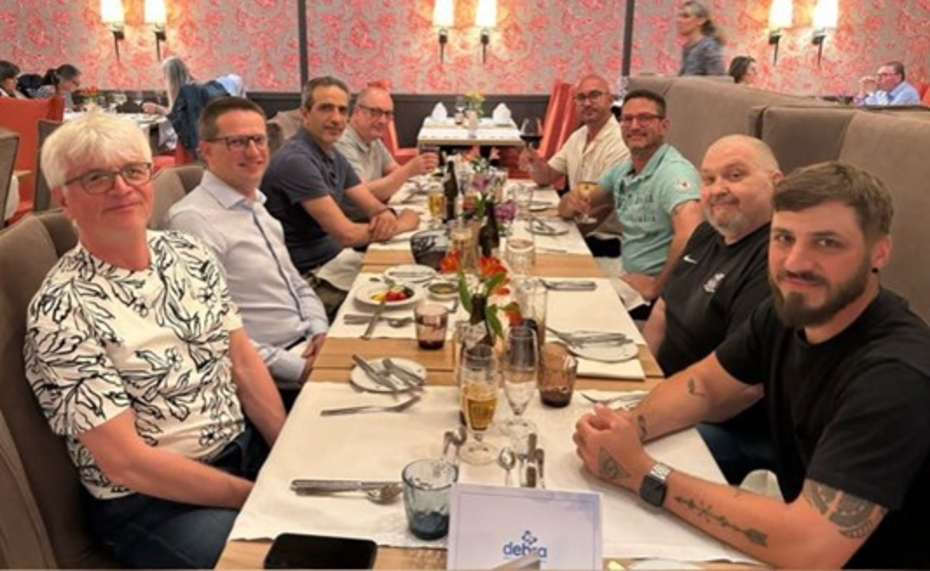 Eine Gruppe von Männern sitzt an einem gedeckten Tisch und schaut in die Kamera