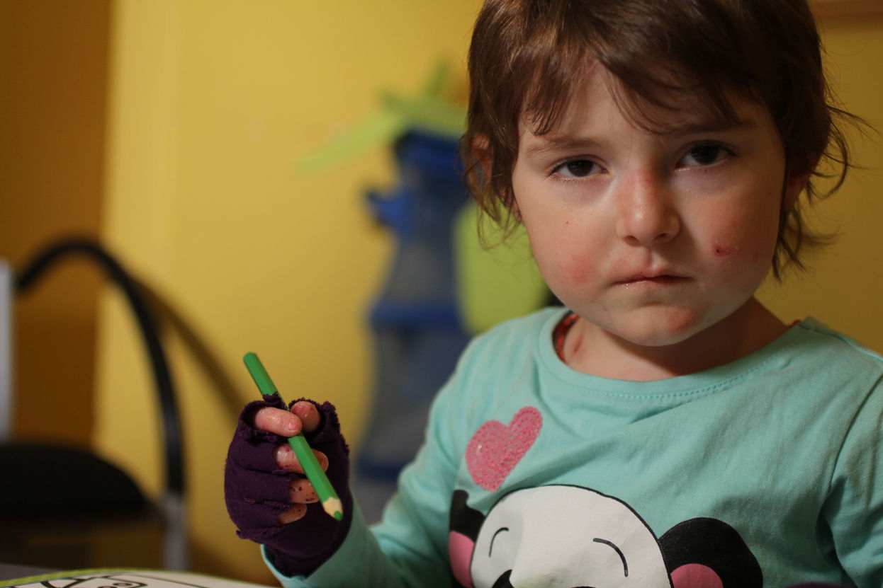 Schmetterlingskind Amelie mit Buntstift in der Hand