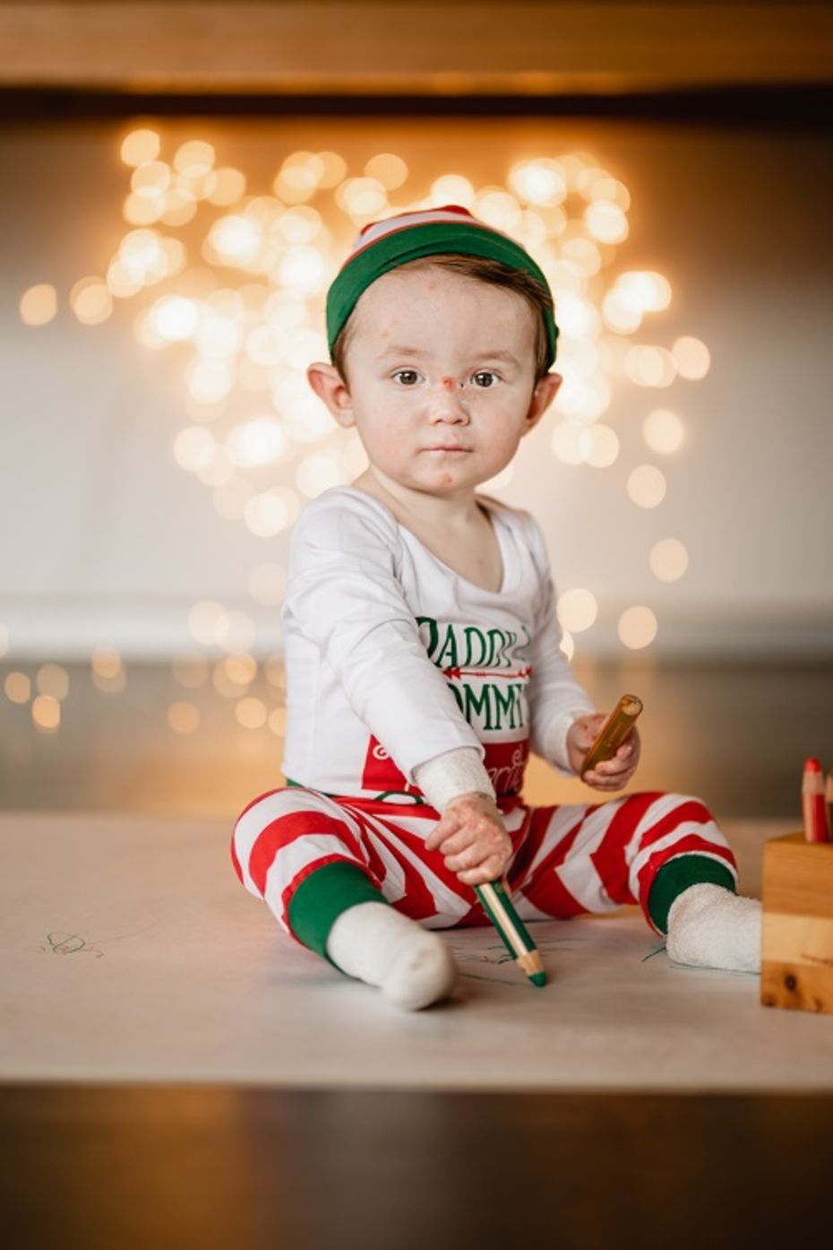 Schmetterlingskind mit Malstift und weihnachtlicher Bekleidung