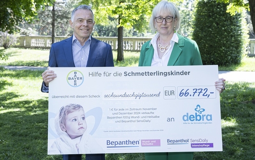 Ein Mann und eine Frau halten einen großen Spendenscheck