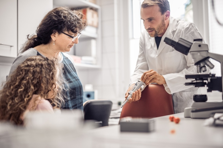 Mutter mit Schmetterlingskind und Forscher unterhalten sich in einem Labor