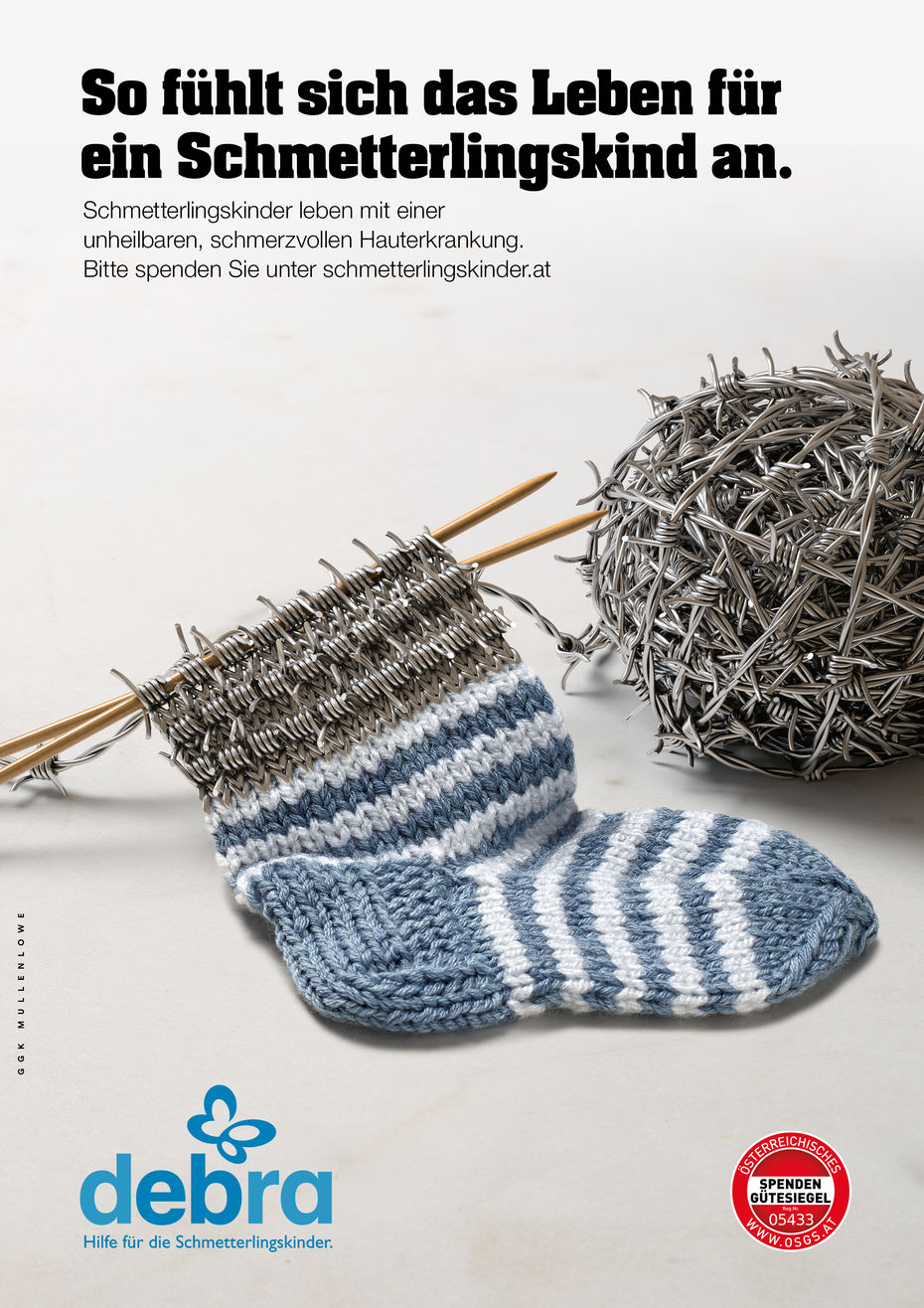 Kampagnensujet Socken, Strickzeug mit einem Kindersocken mit einem Bündchen aus Stacheldraht