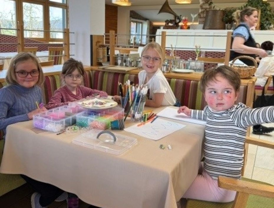 Vier Schmetterlingskinder basteln an einem Tisch