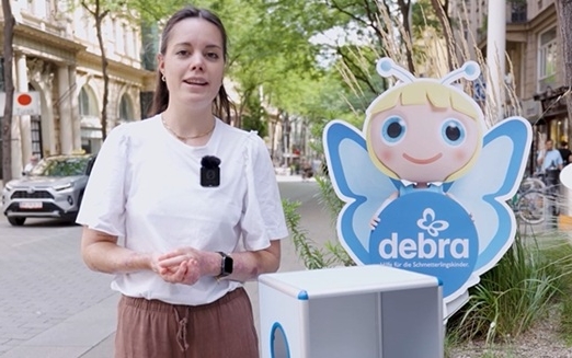 Eine Frau steht auf einer Straße mit einem Pappaufsteller in Form eines blonden Schmetterlingsmädchens