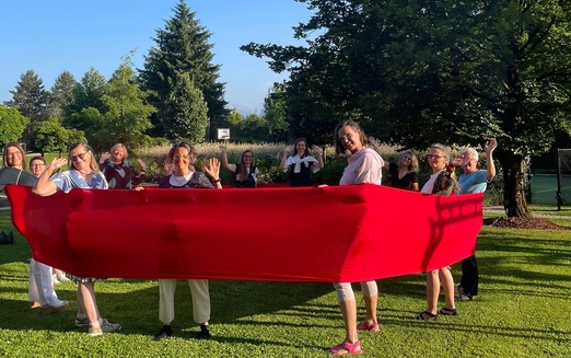 Gruppe von Frauen, die in einem Kreis innerhalb eines breiten roten Bandes stehen