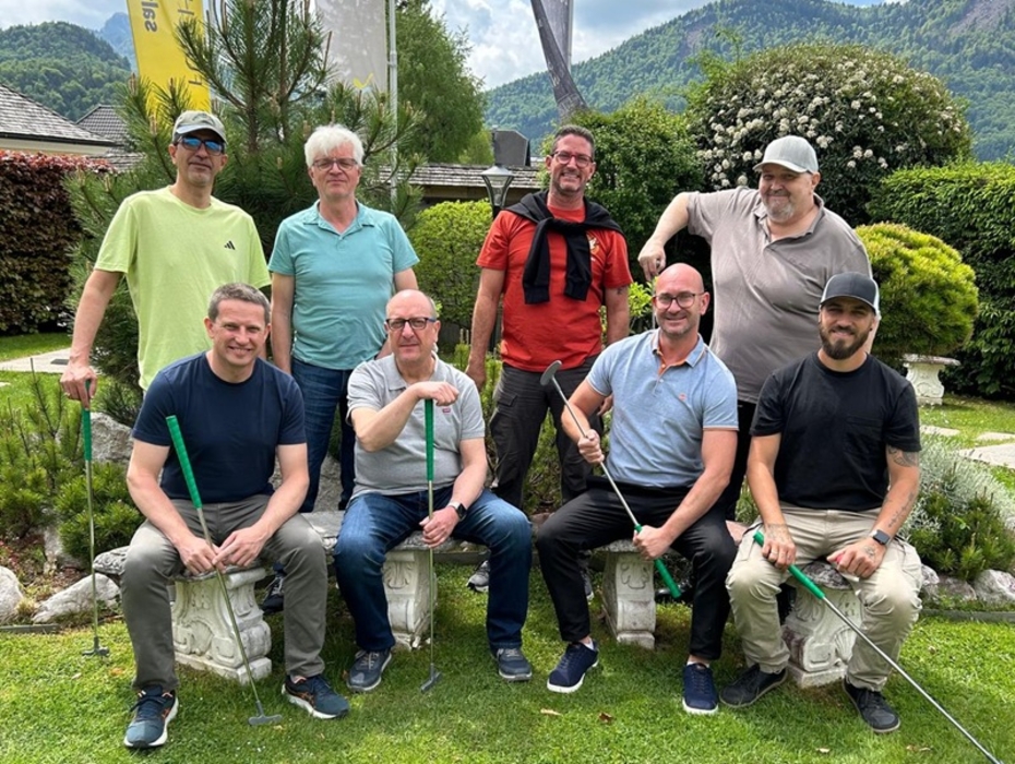 Gruppe von Männern posieren mit Minigolfschlägern auf einer Wiese