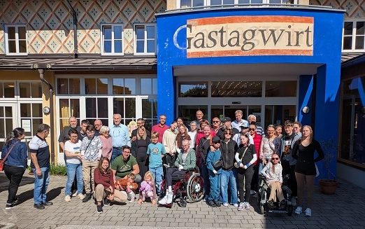 Gruppe von Menschen steht vor dem Eingang eines Gasthauses