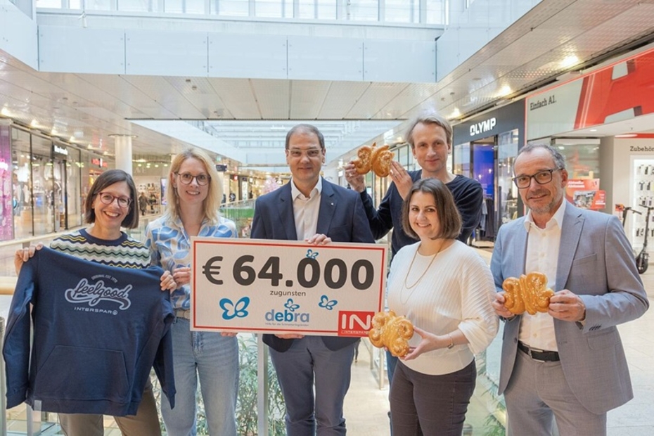 Mehrere Menschen stehen in einem Einkaufszentrum und halten einen Spendenscheck