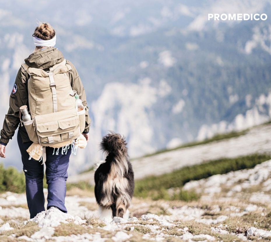 Wanderin mit Rucksack und Hund von hinten