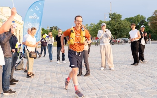 Ein Mann im roten Laufdress läuft aus einer Gruppe von Menschen 