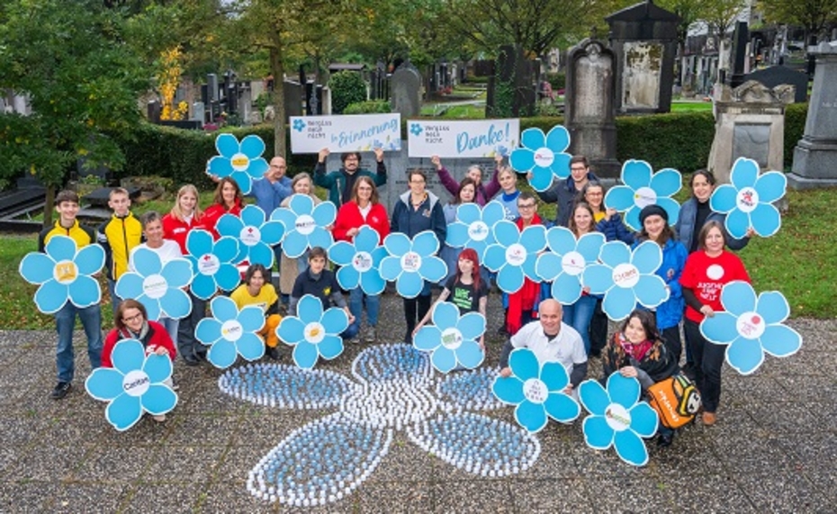 Mehrere Menschen halten große Schilder in Blütenform in den Händen